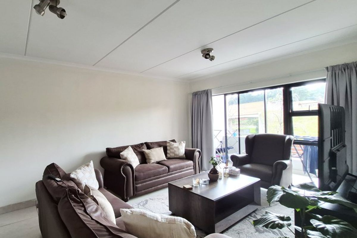 A well-lit living room featuring tiled flooring and a large sliding glass door providing access to the exterior.
