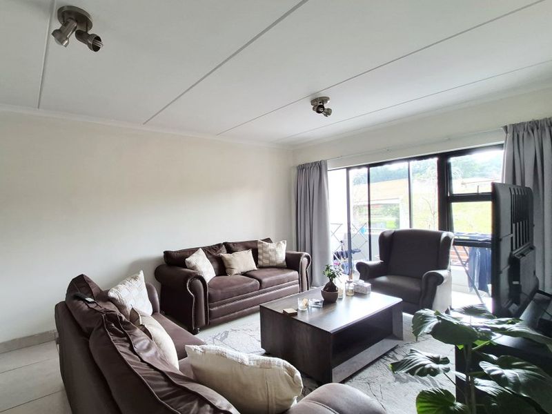 A well-lit living room featuring tiled flooring and a large sliding glass door providing access to the exterior.