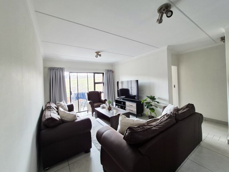 A bright living room featuring tiled flooring and a sliding glass door providing access to an outdoor area.