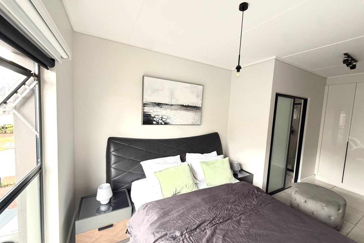 A modern bedroom featuring built-in cupboards, tiled flooring, and large windows that provide ample natural light.