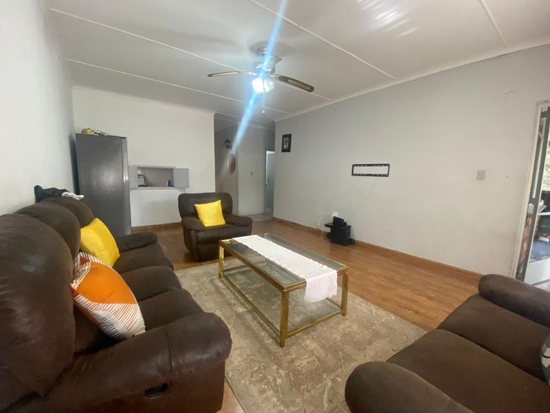 A living room featuring laminate flooring, a ceiling fan, and a convenient pass-through window connecting to the kitchen area.