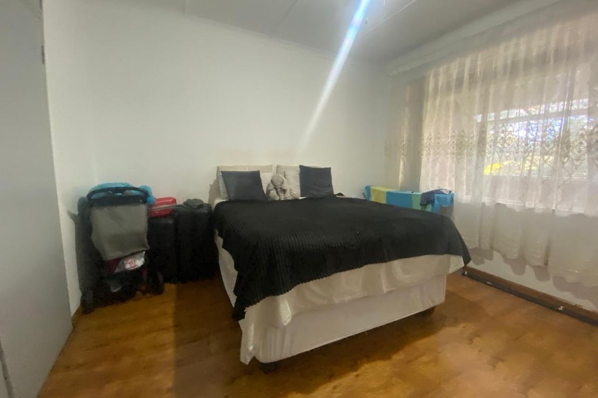 A bedroom featuring laminate flooring and a window with curtain rails, providing a functional space for rest.