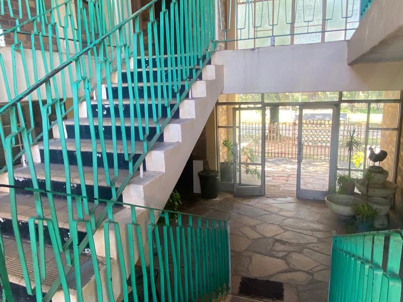 Entrance foyer featuring a stone-floored area with a prominent staircase and metal balustrade, leading to glass doors opening to the exterior.