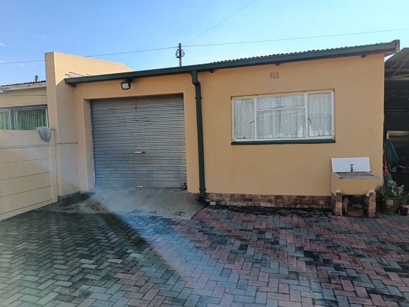Exterior view of a single garage featuring a roller shutter door, an attached utility sink, and a paved driveway area.