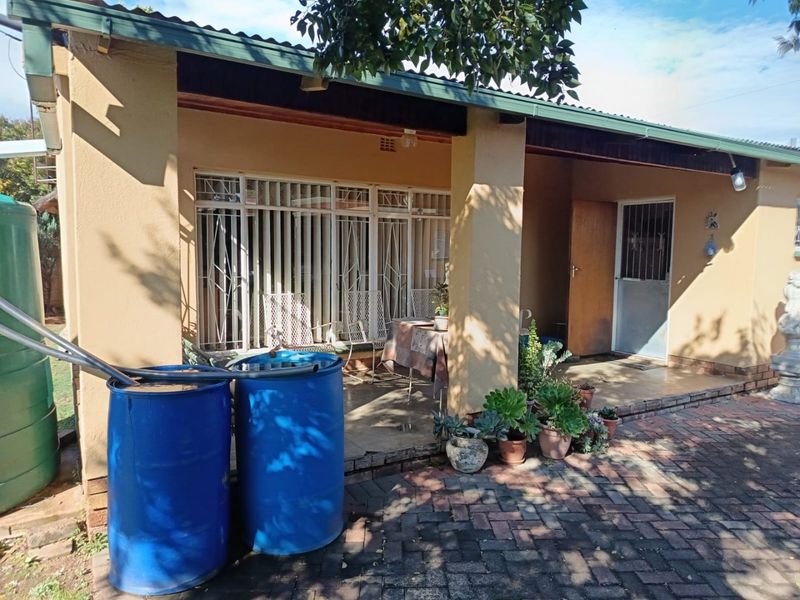 A covered patio area featuring paved flooring and security gates, providing a functional outdoor space with integrated rainwater storage tanks.