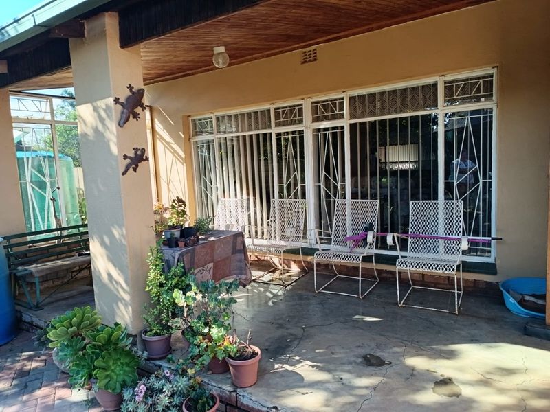A covered patio area featuring a timber ceiling, concrete flooring, and security bars on the windows, providing a functional outdoor space.