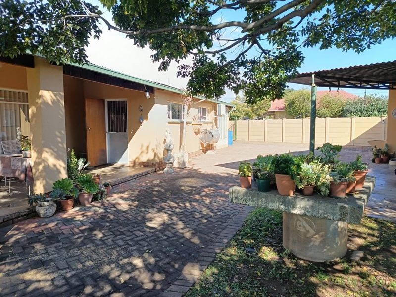 A rear courtyard area featuring paved flooring, a covered patio section, and a precast concrete boundary wall.