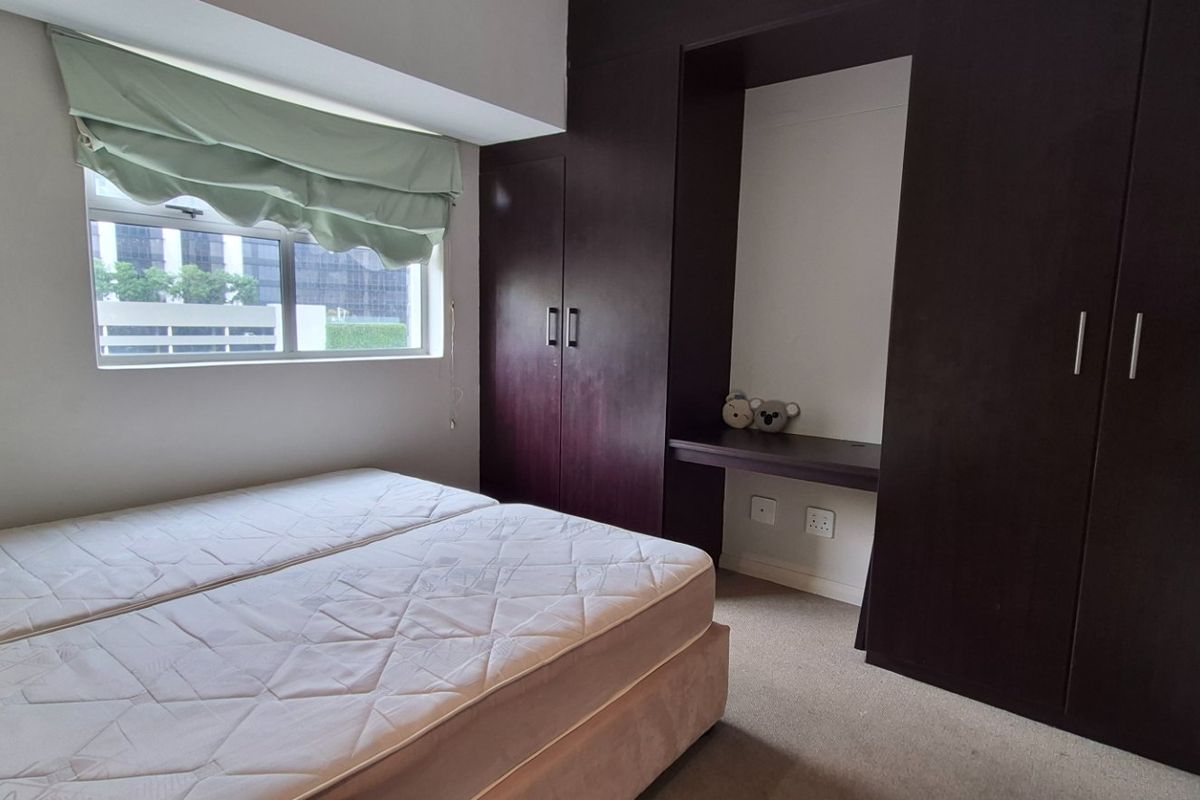 A bedroom featuring dark wood built-in cupboards and an integrated desk area, complemented by neutral walls and carpeted flooring.