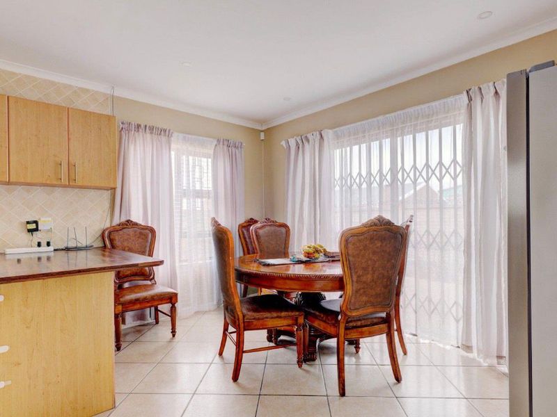 Open-plan dining area featuring tiled flooring, built-in cabinetry, and large windows with security gates, providing a functional and well-lit space.