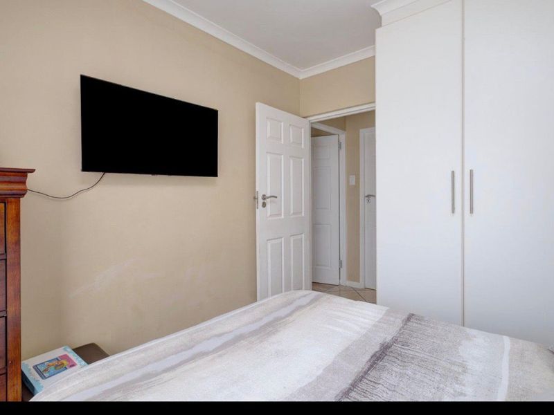 A bedroom featuring a built-in wardrobe, neutral wall finishes, and access to an adjoining hallway.