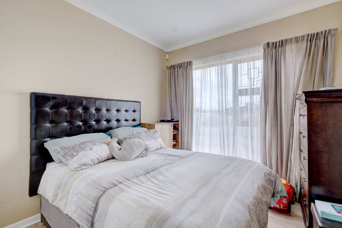 A well-lit bedroom featuring neutral wall tones, coving, and a large sliding glass door providing natural light and access to the exterior.