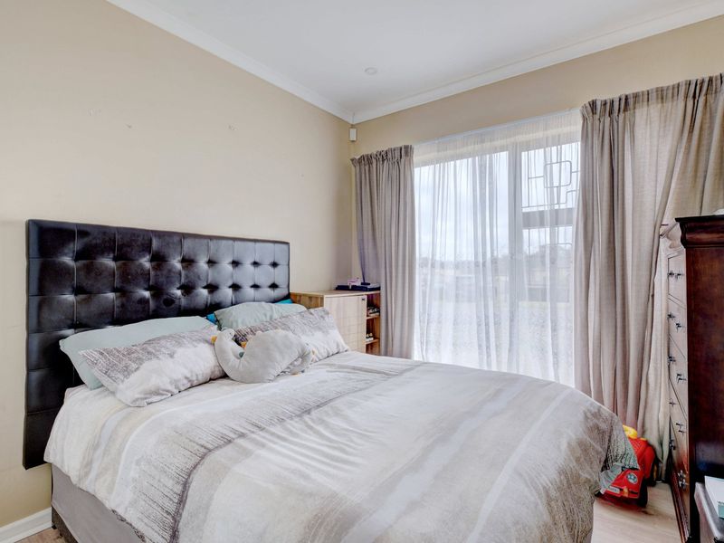 A well-lit bedroom featuring neutral wall tones, coving, and a large sliding glass door providing natural light and access to the exterior.