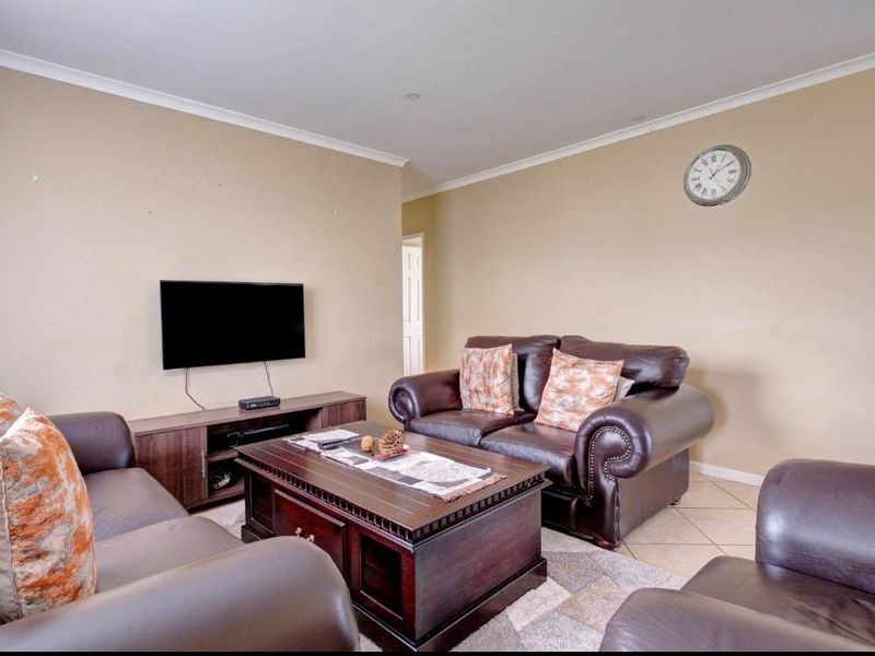 A comfortable living room featuring neutral wall tones, tiled flooring, and decorative cornice detailing, providing a functional and inviting space.