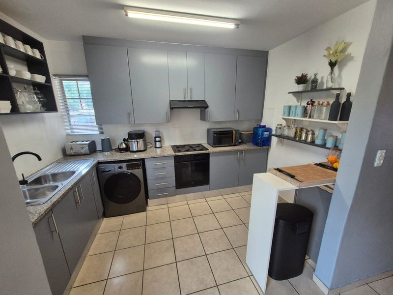 A functional kitchen featuring grey built-in cabinetry, granite countertops, a built-in oven with hob, and tiled flooring.