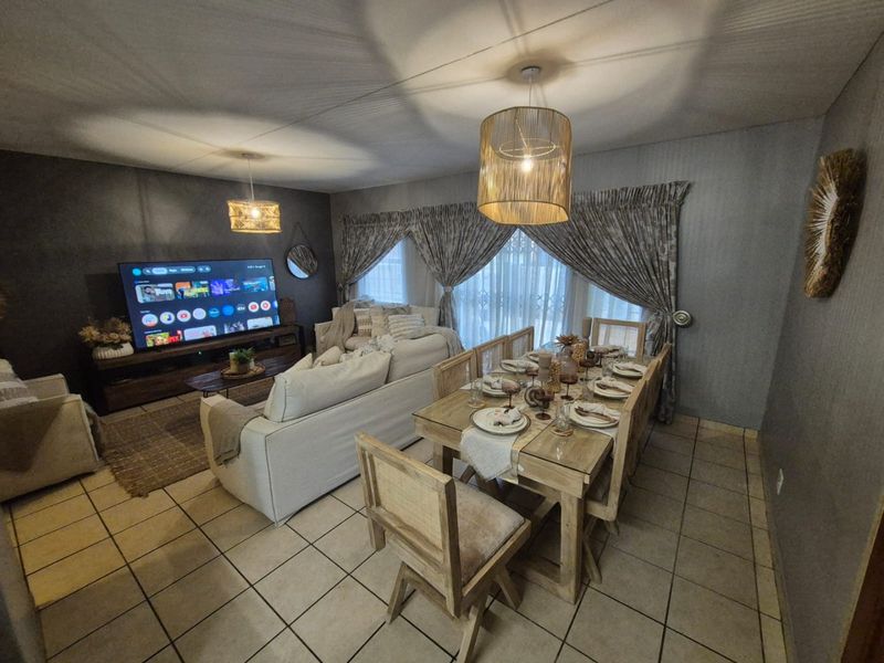Spacious open-plan living and dining area featuring ceramic floor tiles and decorative pendant lighting, creating a comfortable and functional space for daily living.