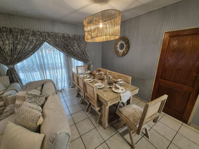 Open plan living and dining area featuring ceramic floor tiles and a solid wood door, providing a functional space for family gatherings.
