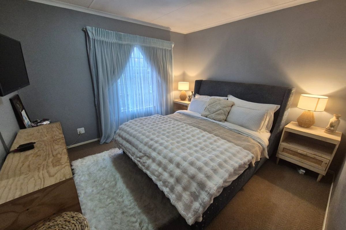 A cozy bedroom featuring grey walls, carpeted flooring, and a classic cove cornice finish, providing a comfortable and neutral sleeping space.