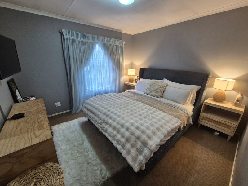 A cozy bedroom featuring grey walls, carpeted flooring, and a classic cove cornice finish, providing a comfortable and neutral sleeping space.