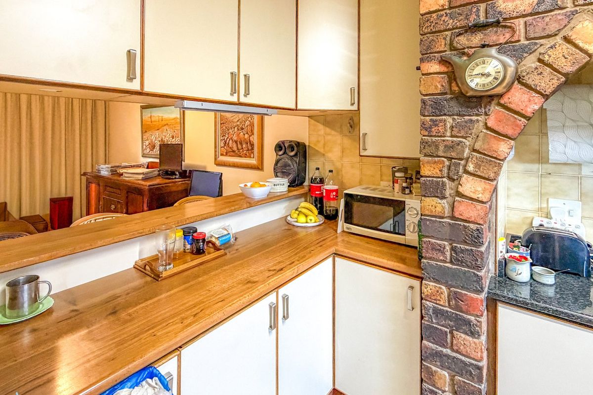 A compact kitchen featuring wooden countertops, white cabinetry, and a distinctive brick archway, offering a functional layout with a breakfast bar pass-through.