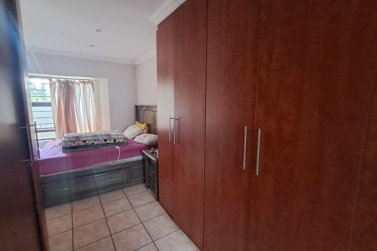 A bedroom featuring tiled flooring, recessed downlights, and extensive built-in wooden cupboards providing ample storage space.
