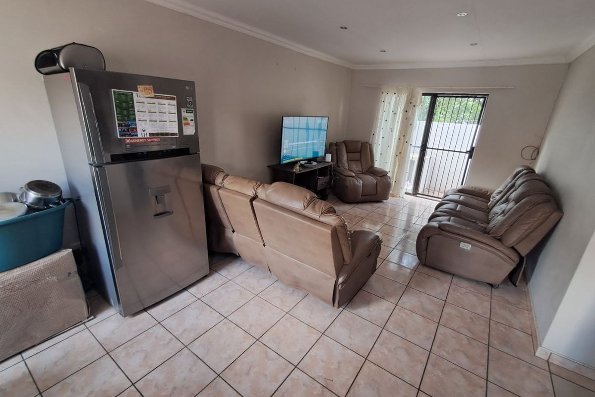 A functional living room featuring tiled flooring, recessed lighting, and a sliding glass door with a security gate providing access to the exterior.