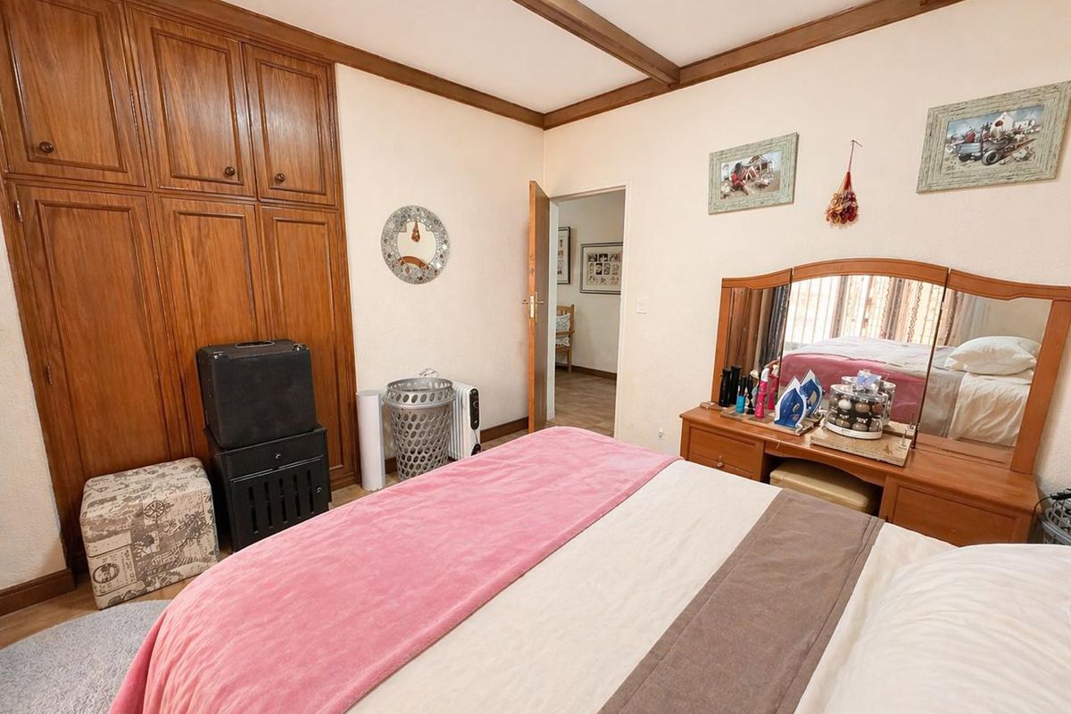 A bedroom featuring built-in wooden wardrobes and exposed ceiling beams, offering a traditional aesthetic with potential for modern updates.