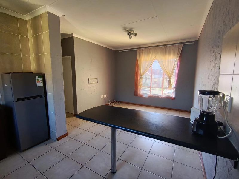 Open plan living area featuring tiled flooring and a built-in breakfast bar, offering a functional space ready for modernization.