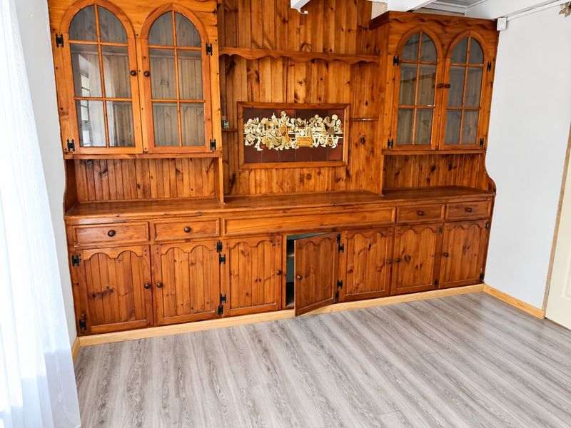 A living area featuring extensive built-in wooden cabinetry and modern laminate flooring, offering significant storage space.