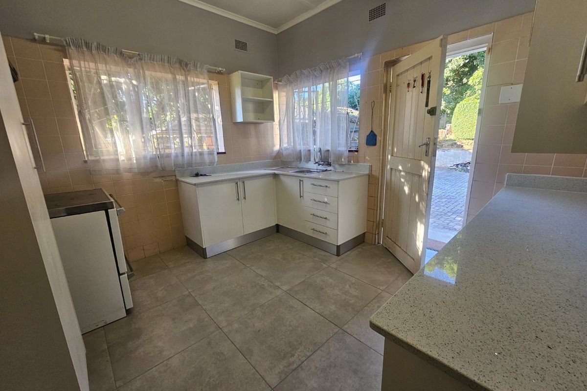 Functional kitchen featuring stone countertops, built-in cabinetry, tiled splashbacks, and direct access to the rear exterior area.