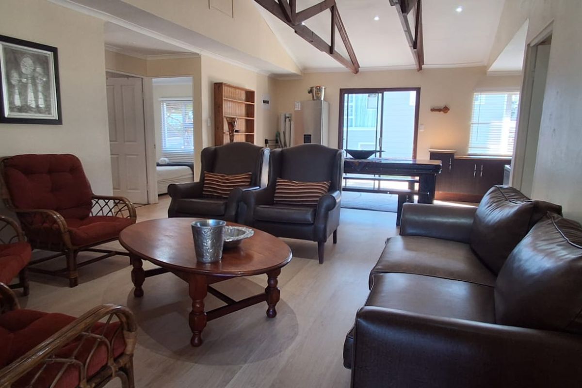 Spacious open-plan living area featuring high vaulted ceilings with exposed timber trusses, laminate flooring, and direct access to the outdoor area.