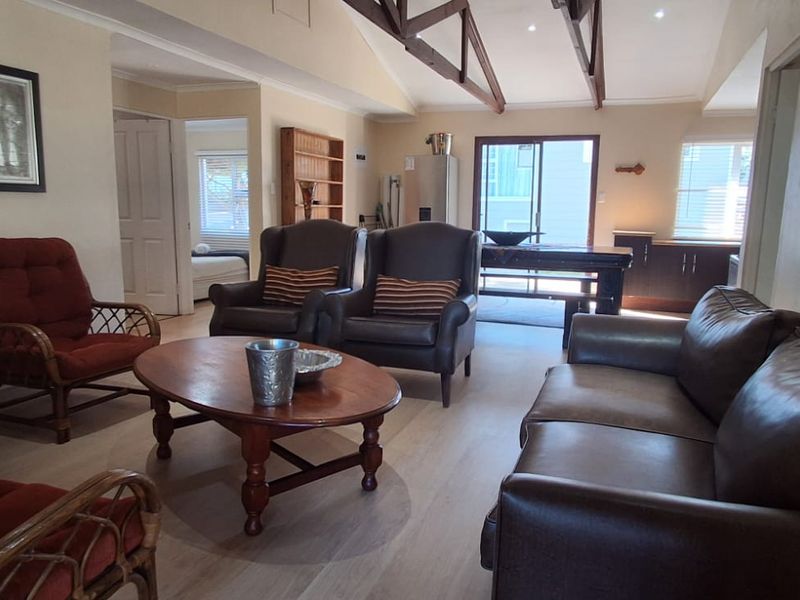 Spacious open-plan living area featuring high vaulted ceilings with exposed timber trusses, laminate flooring, and direct access to the outdoor area.