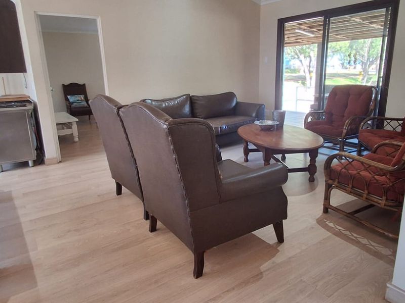 Open-plan living area featuring light laminate flooring and sliding glass doors leading to an outdoor space, adjacent to a functional kitchen area.