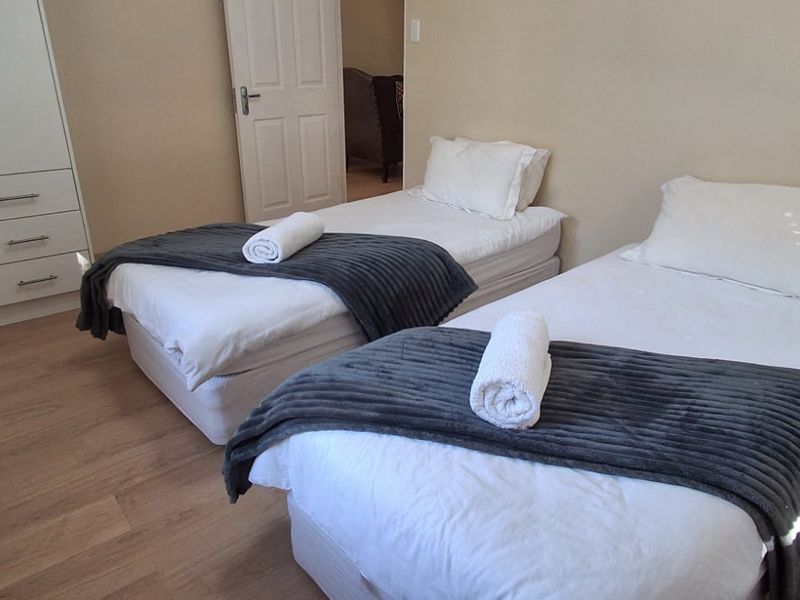 A well-maintained bedroom featuring light laminate flooring, neutral walls, and a functional built-in wardrobe.