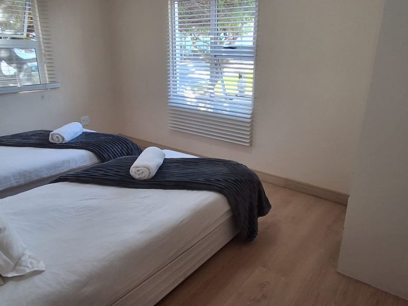 A functional bedroom featuring laminate flooring and venetian blinds, providing a neutral space with natural light.