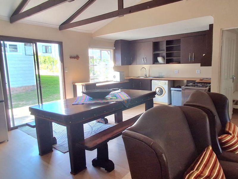 Open-plan living and kitchen area featuring dark wood cabinetry, exposed timber ceiling beams, and direct access to the garden through sliding glass doors.