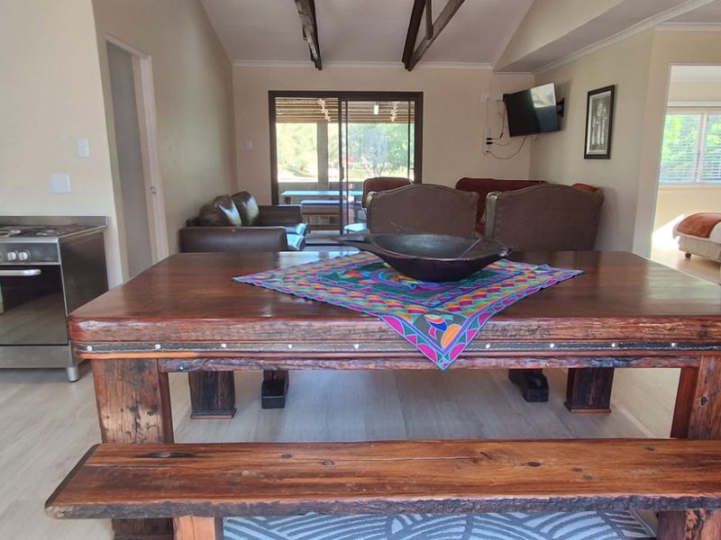 Open-plan living and kitchen area featuring exposed timber ceiling beams, modern laminate flooring, and direct access to the outdoor patio through sliding glass doors.