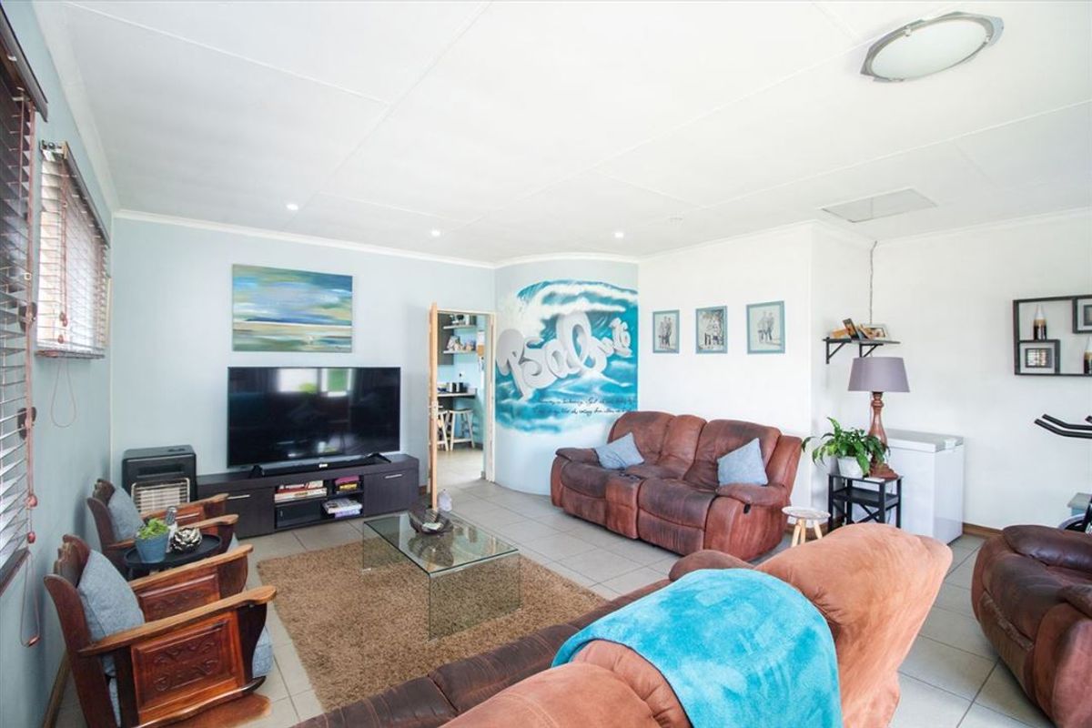 A spacious living room featuring tiled flooring, recessed lighting, and a neutral color palette, providing a comfortable and functional family living space.
