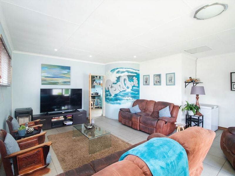 A spacious living room featuring tiled flooring, recessed lighting, and a neutral color palette, providing a comfortable and functional family living space.