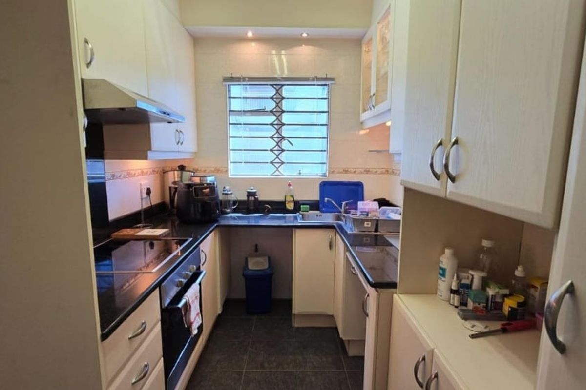 A compact, functional kitchen featuring built-in cabinetry, granite countertops, an electric hob, and an integrated oven with an extractor fan.