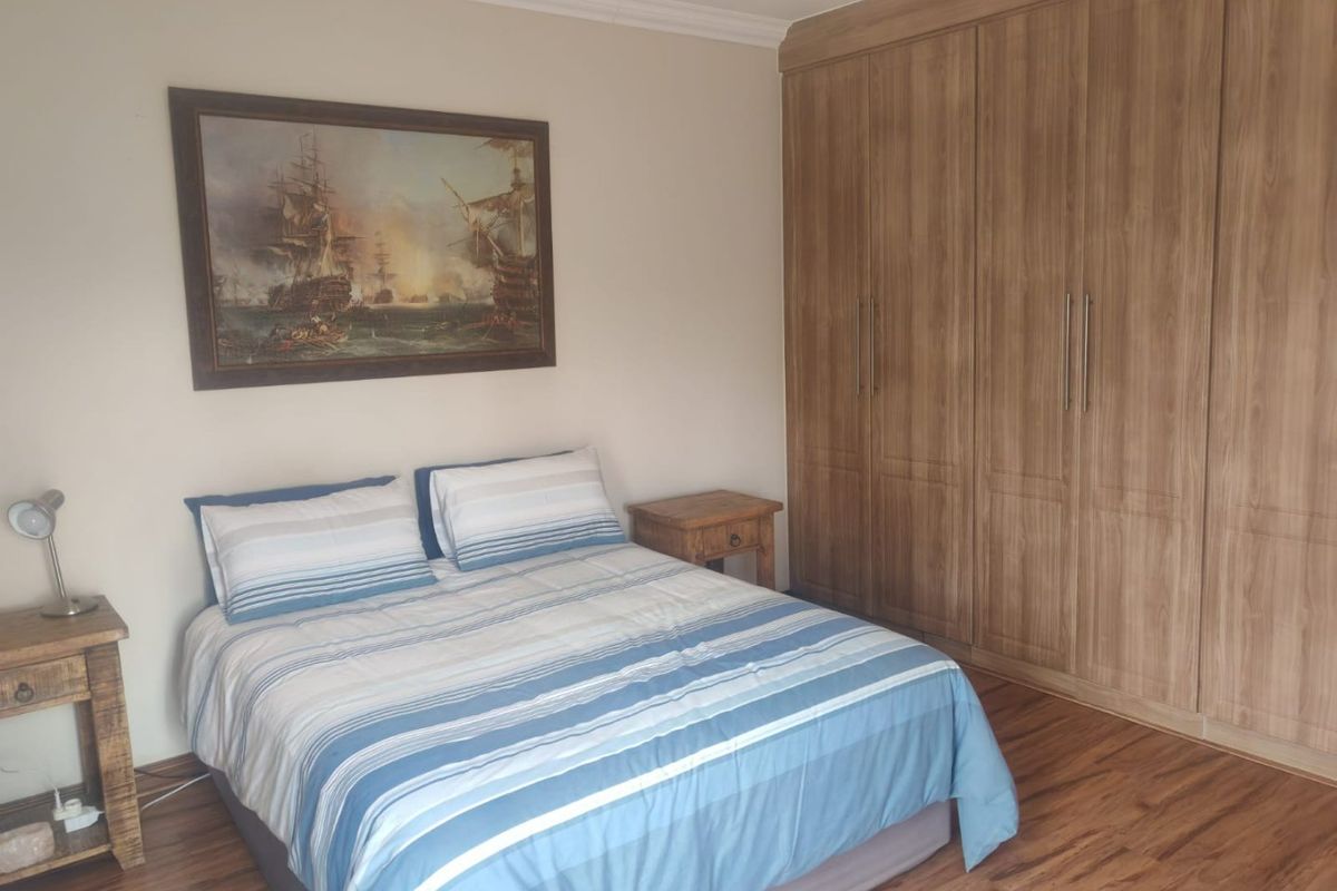 A well-maintained bedroom featuring wood-look laminate flooring and extensive floor-to-ceiling built-in cupboards providing ample storage space.