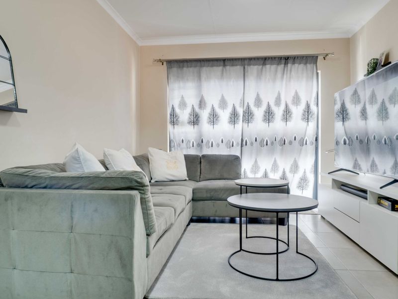 A well-maintained living room featuring tiled flooring and a sliding door providing access to the exterior.