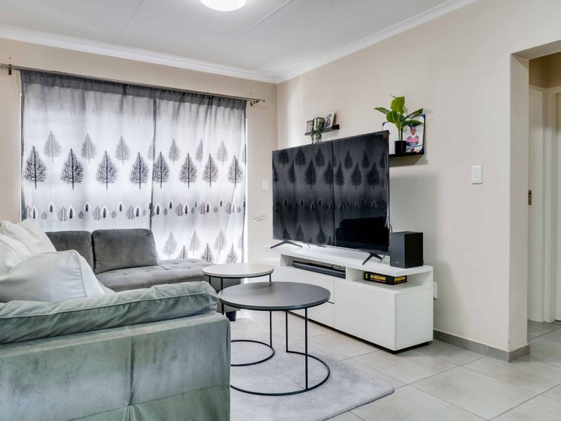 A well-maintained living room featuring neutral tiled flooring and classic cove cornicing, providing a clean and functional space.