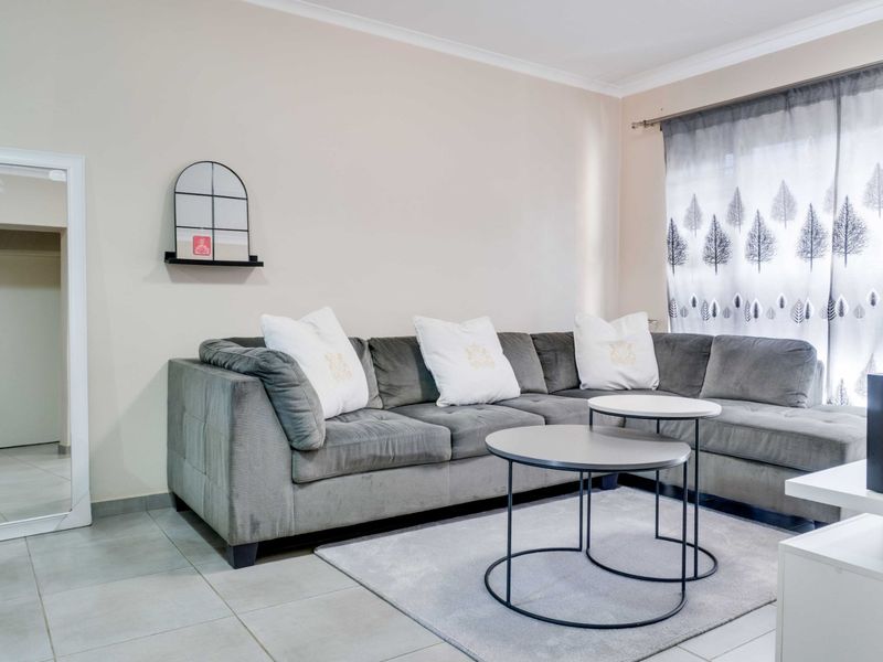 A well-maintained living room featuring neutral wall tones, tiled flooring, and classic cove cornicing, providing a comfortable and functional living space.