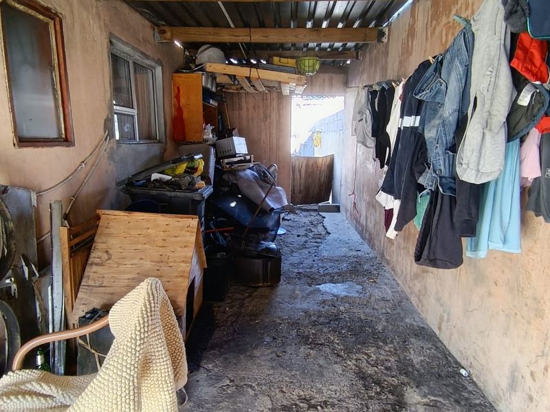 A utilitarian storage or service area featuring exposed timber beams, corrugated roofing, and concrete flooring, currently used for general storage.