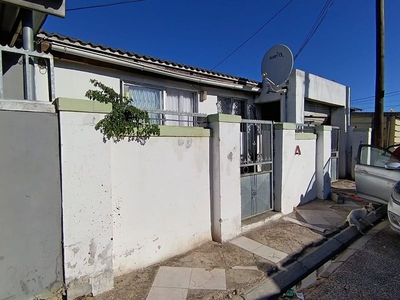 Front exterior view of the property featuring a boundary wall, security gate, and satellite dish, showing signs of wear and maintenance requirements.