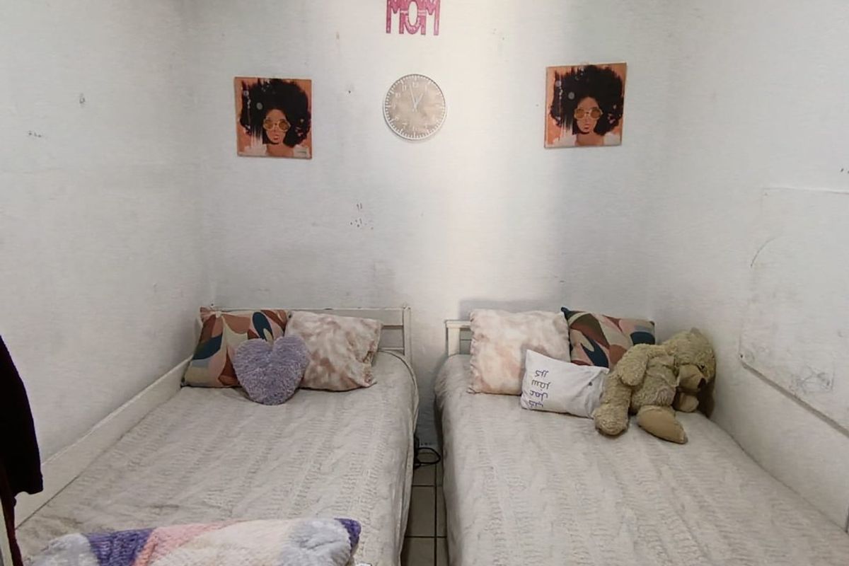 A compact bedroom featuring tiled flooring and white walls, currently configured with two single beds.