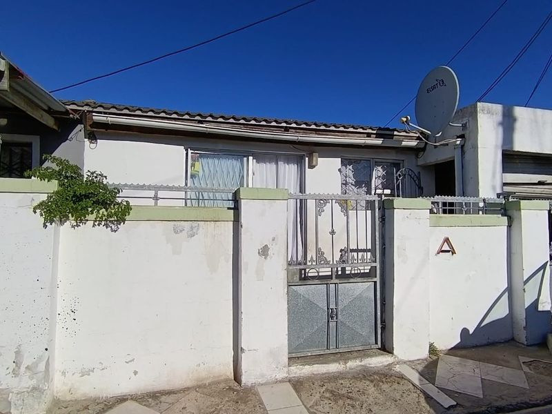 Front exterior view of the property featuring a perimeter wall with a metal security gate and tiled roof structure.