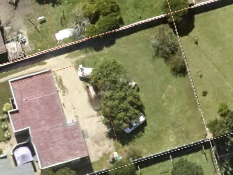 An aerial view of the residential land parcel showing the existing building footprint, driveway access, and established garden area with boundary fencing.