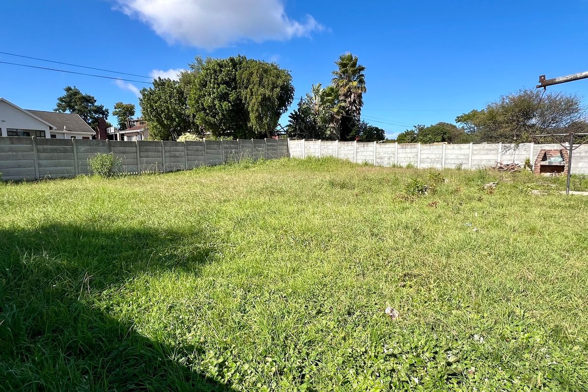 A spacious, undeveloped residential plot featuring a precast concrete boundary wall and a built-in brick braai area, currently covered in overgrown grass.