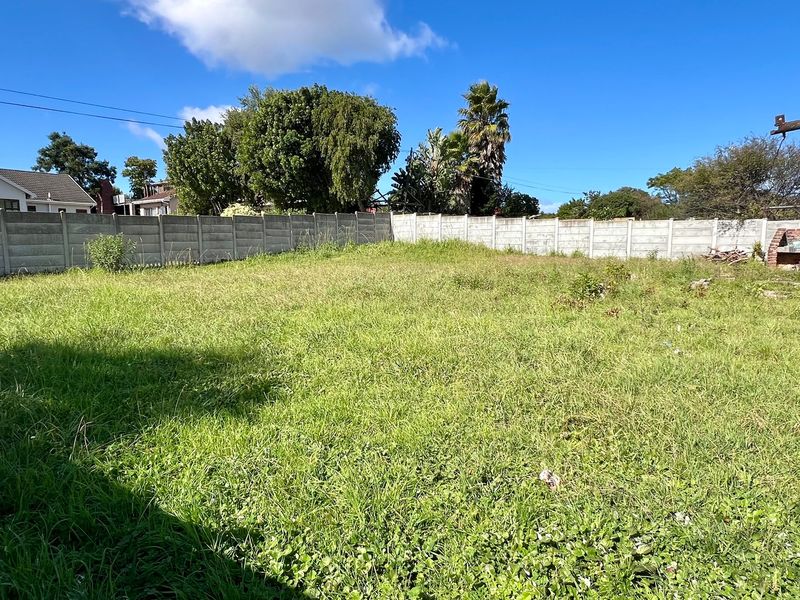 A spacious, undeveloped residential plot featuring a precast concrete boundary wall and a built-in brick braai area, currently covered in overgrown grass.